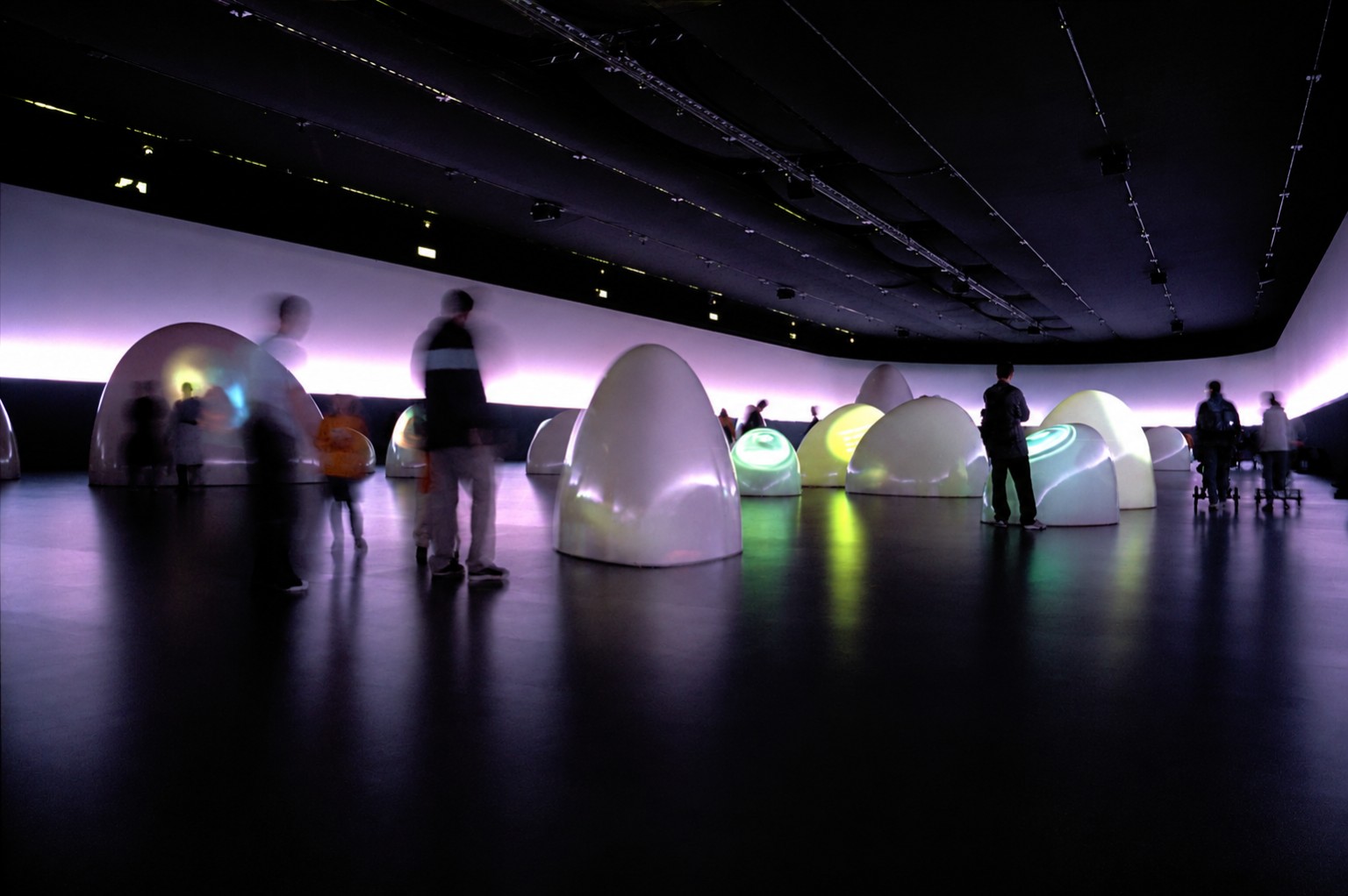 Visitors moving through a dark luminous art installation