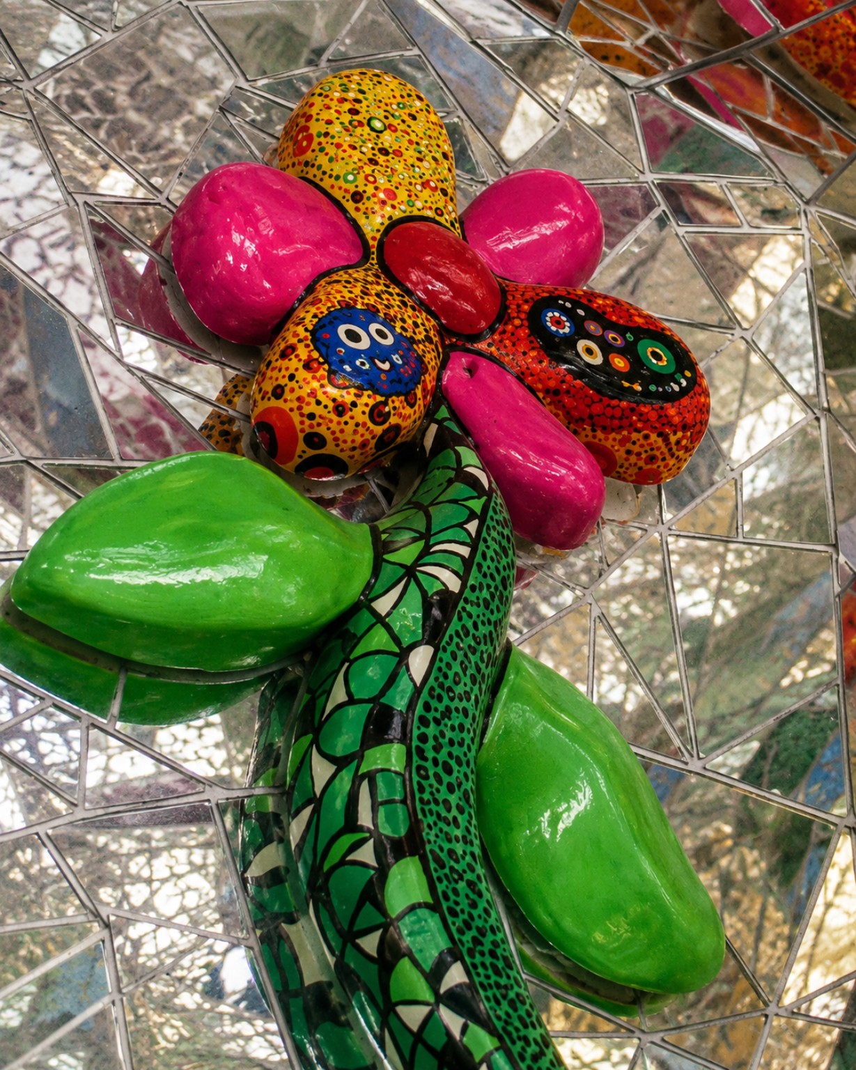 Colourful sculptural flower surrounded by mirrored mosaic