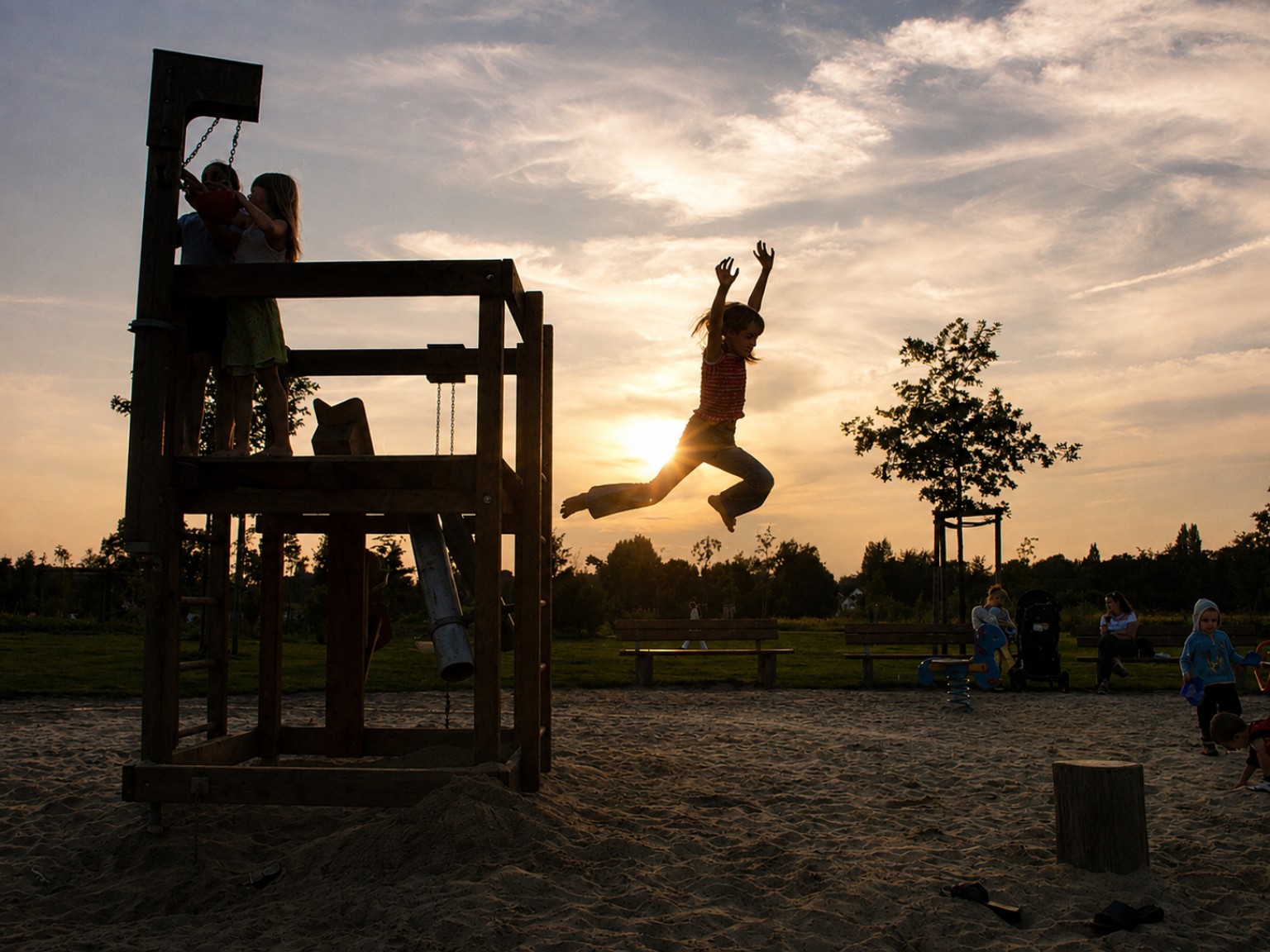 A child jumping from a playground structure into warm evening light